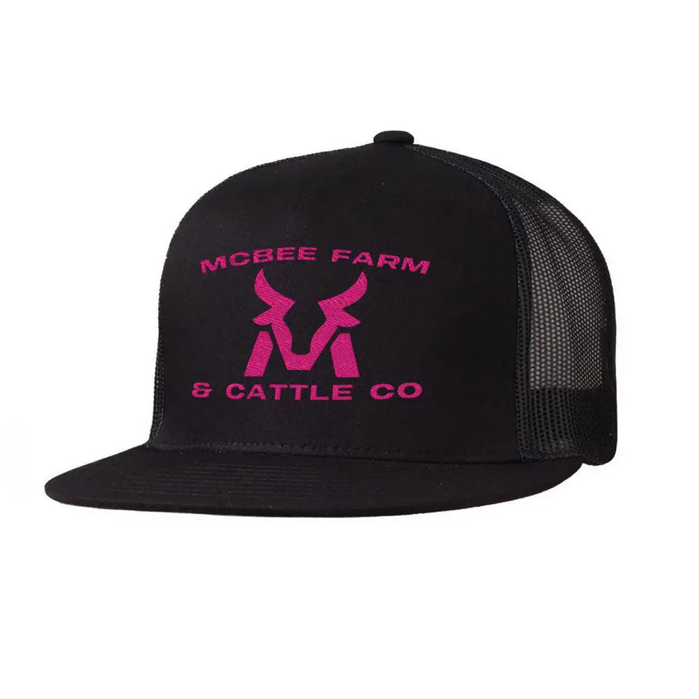 The McBee Farms Flat Bill Hat by McBee Farm & Cattle Co is a high-profile black trucker cap with a mesh back, featuring pink text and a logo with MCBEE FARM & CATTLE CO and a stylized cattle horn design on the front. It has an adjustable closure for the perfect fit.
